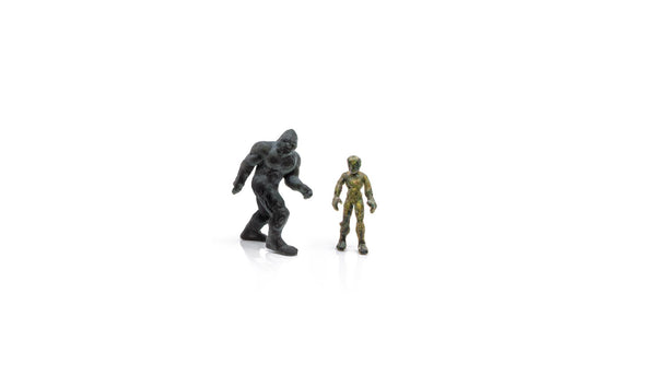 Two small detailed collectible figures side by side on a white background, featuring a black monster and a green humanoid, representing Woodland Scenics A2863 Find Me Figures Monsters Figures - O Scale, veteran-owned business supporting STEM education and hobby enthusiasts.