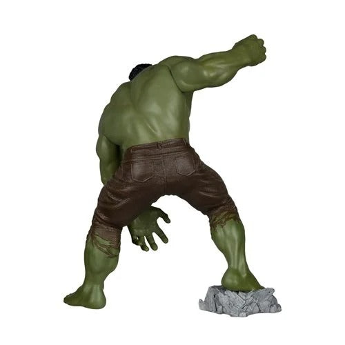 Hulk action figure posed in a dynamic crouching stance, wearing brown pants and standing on a gray rock base against a plain white background.