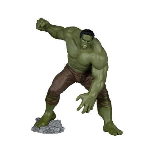Hulk action figure posed in a dynamic crouching stance on a gray rock base, with green skin and brown pants, isolated on a white background.