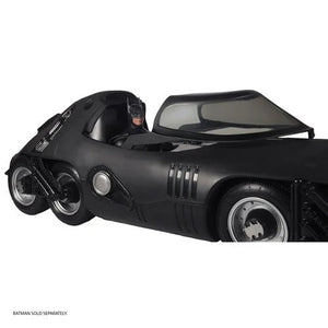 Black Batmobile toy with a person inside on a white background