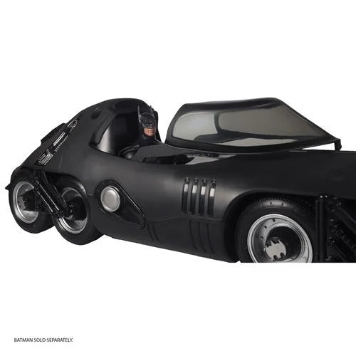 Black Batmobile toy with a person inside on a white background