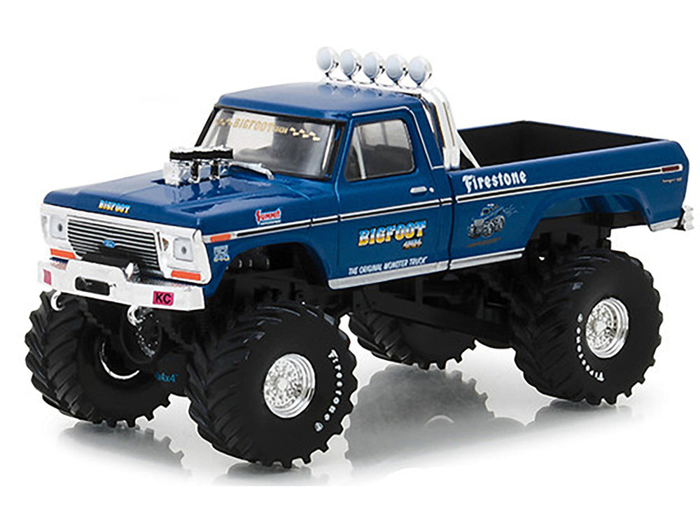 Blue Bigfoot monster truck model with oversized wheels next to its packaging on a white background