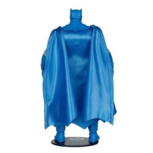 A blue Batman figure or collectible statue shown from the back, wearing a flowing cape and cowl, standing on a round black base against a plain white background.