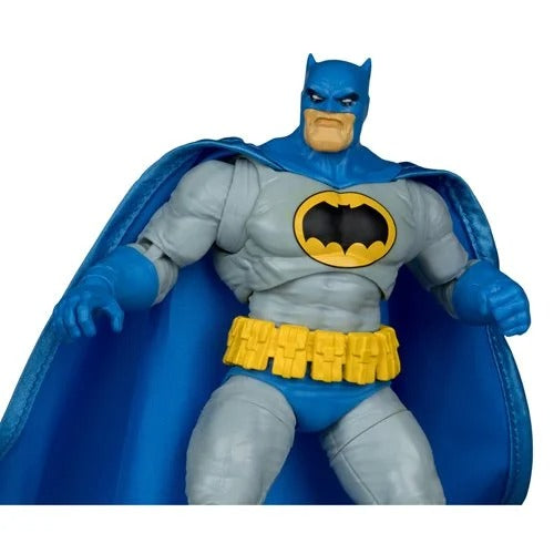 Batman action figure with a blue cape, gray suit, yellow utility belt, and black-and-yellow cowl, shown against a plain white background.