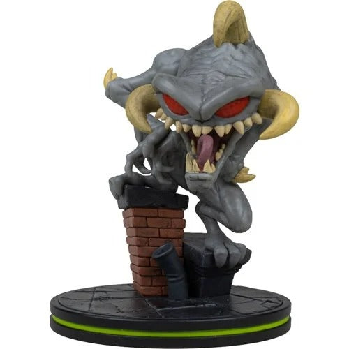 A stylized collectible figurine of a gray monster with red eyes, yellow horns, and a wide open mouth showing sharp teeth and a pink tongue, perched on a brick chimney atop a black circular base with a bright green ring.