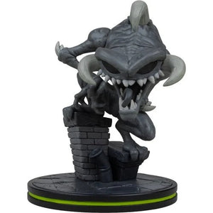 A stylized collectible figurine of a dark gray monster or goblin crouching over a brick wall on a round black base with a bright green ring, photographed against a plain white background.