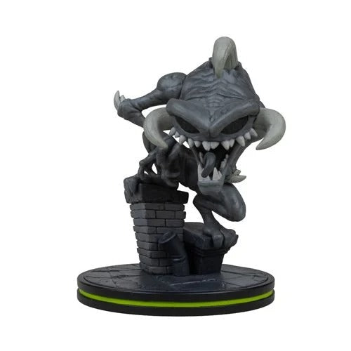 A dark gray monster figurine with horns, sharp teeth, and a crouched aggressive pose, mounted on a round black base with a bright green ring detail, isolated on a white background.