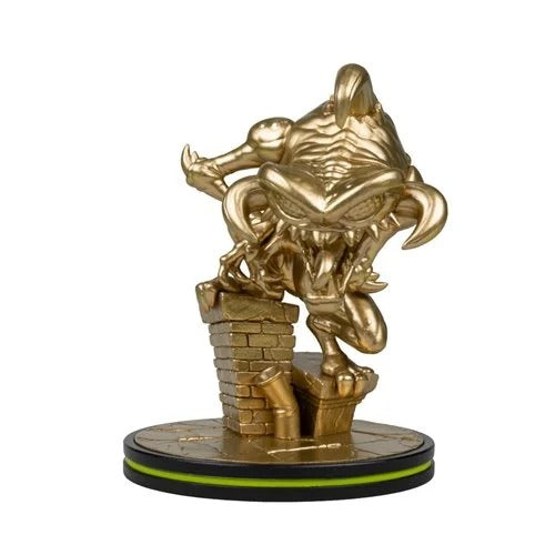 A gold-colored collectible figurine of a monstrous creature climbing a brick wall, mounted on a circular black and gold base with a thin green accent line, set against a plain white background.