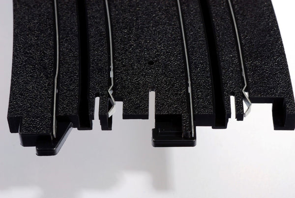 Echo Six Hobbies AFX Racing Close-up of black HO Slot Car track with textured surface on a white background