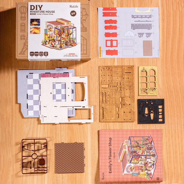 DIY miniature house kit components on a wooden surface