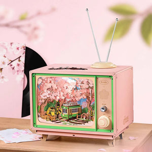 Pink vintage-style television with cherry blossom design on screen against a pink background