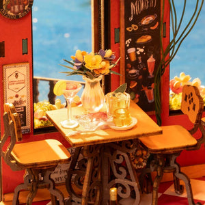 Miniature table setting with drinks and flowers in a dollhouse-style room.