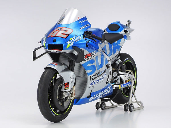 Blue and white Suzuki motorcycle model on a stand with a white background