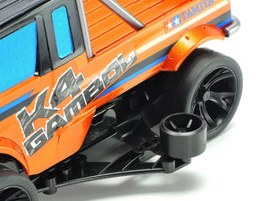 Close-up of an orange model truck with 'K4 Gambol' and 'Tamiya' branding on a white background.