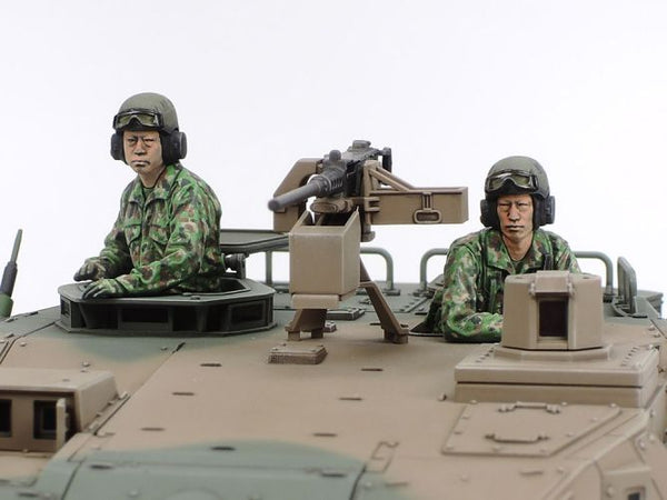 Two soldiers in camouflage uniforms sitting on a model military vehicle with a white background
