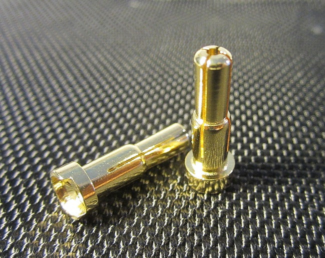 Two gold bullet connectors on a textured black surface