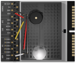 Close-up of a compact controller board with labeled pins connected by colored wires on a black prototype breadboard, illustrating hands-on STEM learning for Make: Getting Started with Oxocard Connect - PDF.